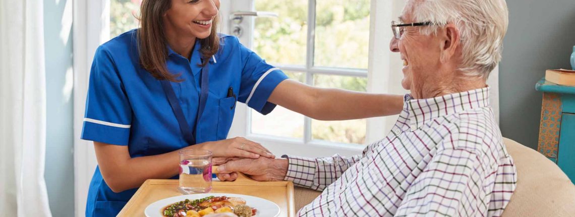 Elderly care home patient being fed by nurse